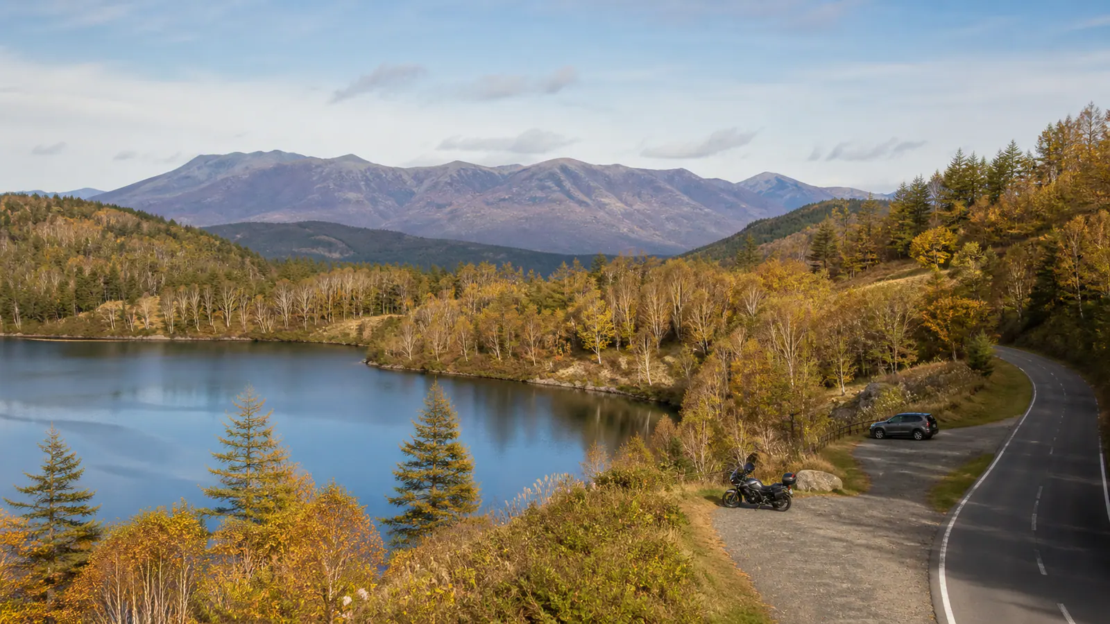 湖と色づき始めた木々のそばを走るビーナスラインの風景