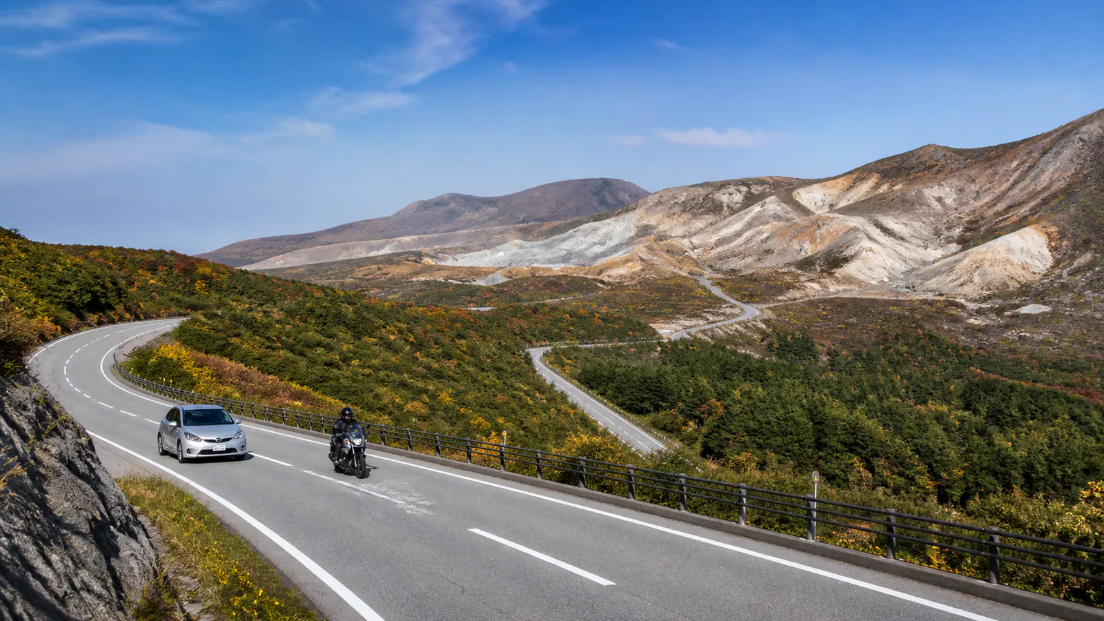 火山性の高原を走る車とバイク