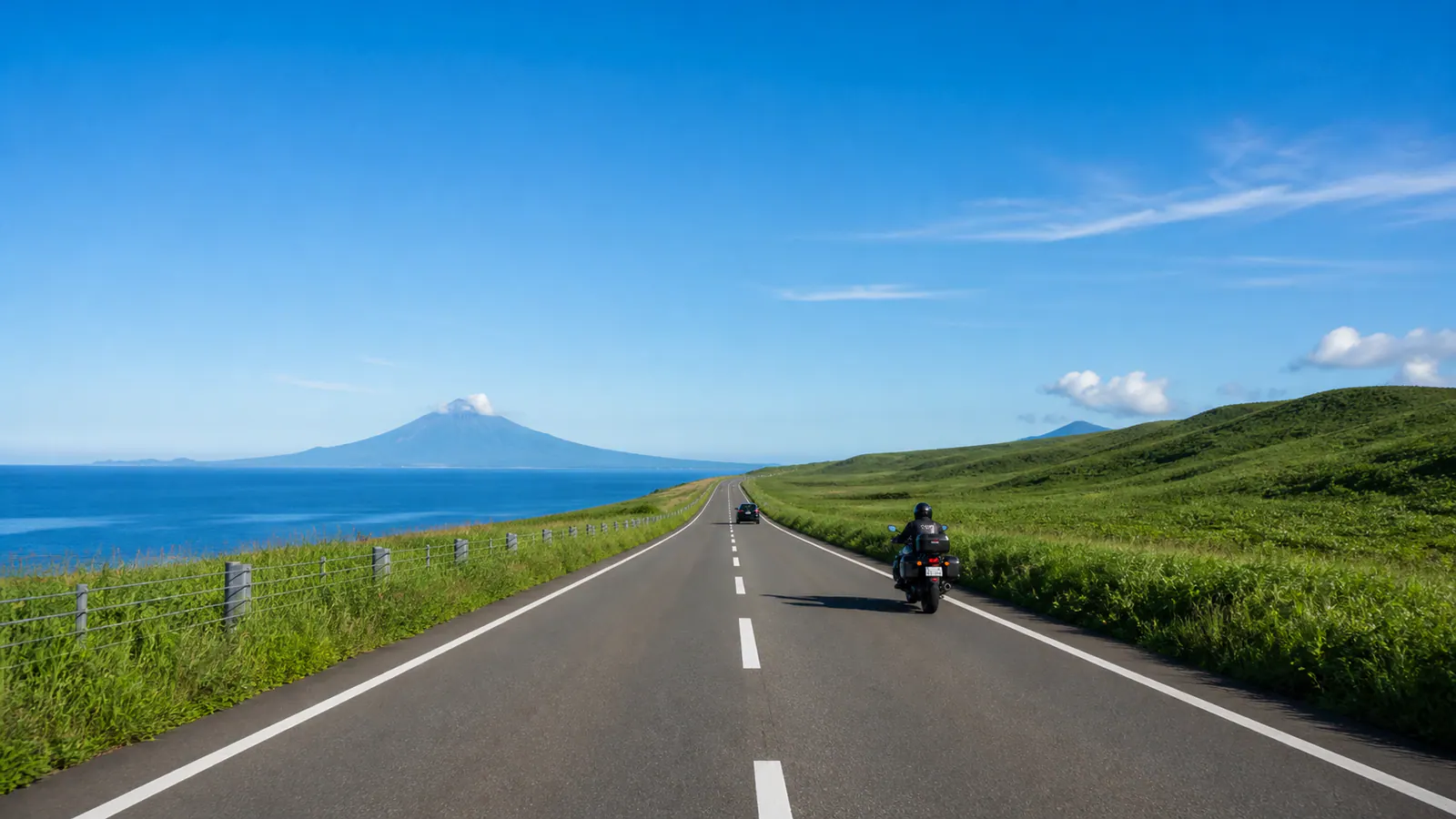 日本海と原野の間を延びるオロロンラインを走る車とバイク