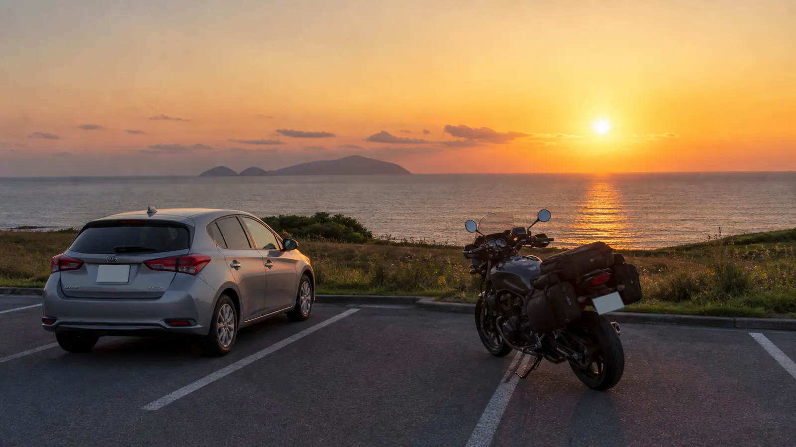 日本海に沈む夕日を望む休憩場所の車とバイク