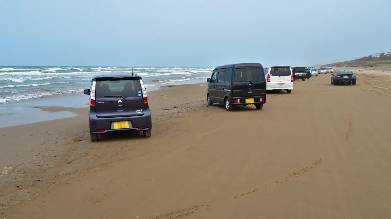 日本海沿いの締まった砂の走行帯を進む車列
