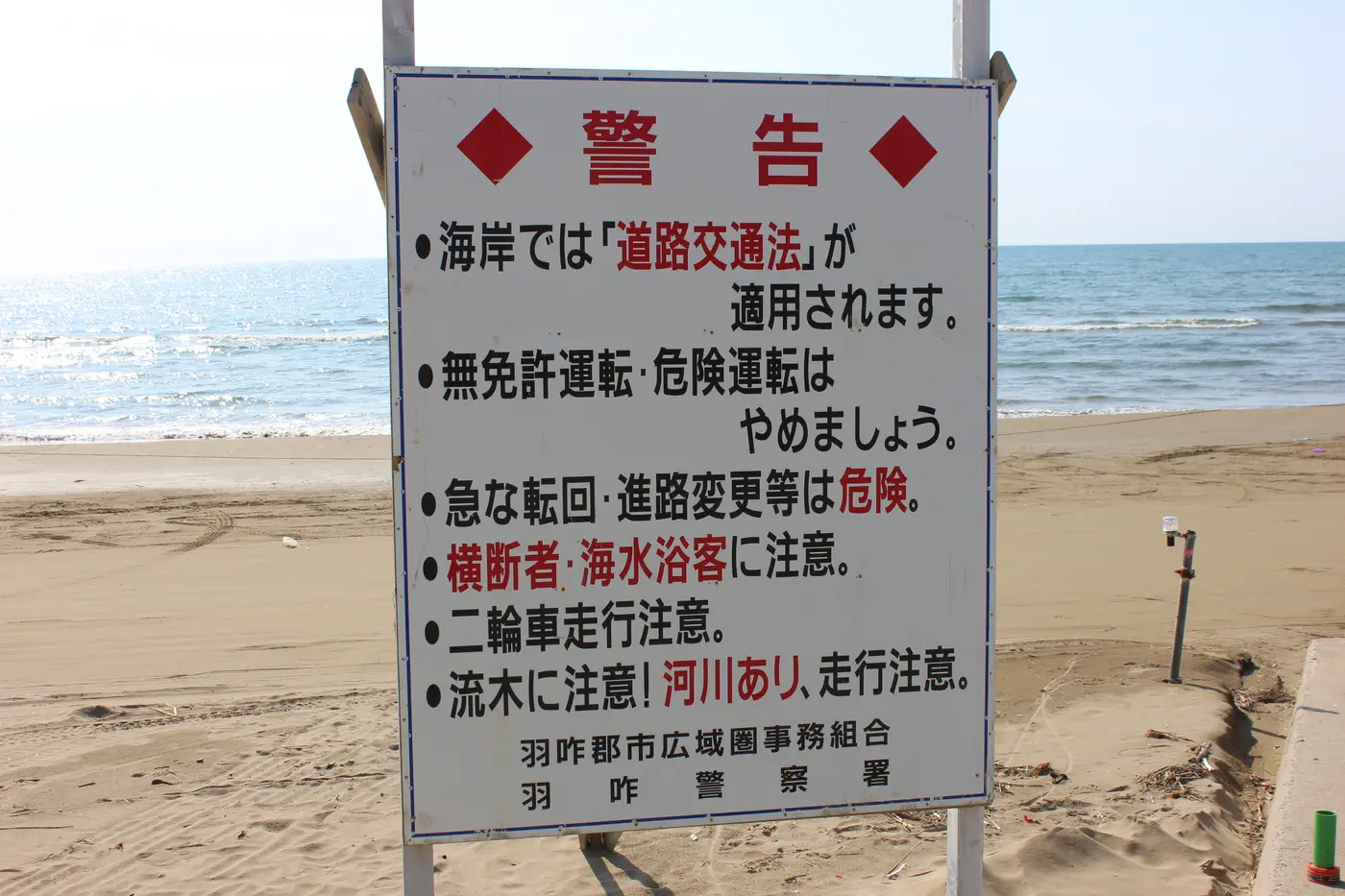海岸で道路交通法と二輪車への注意を知らせる警告看板