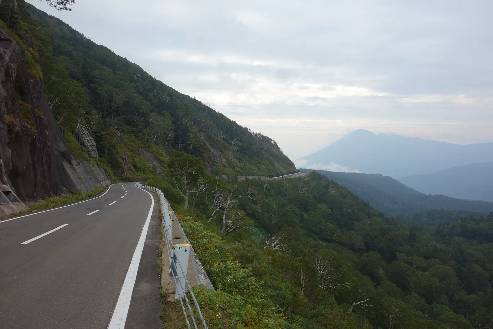 八幡平アスピーテラインの山腹を縫う道路と遠くの山並み
